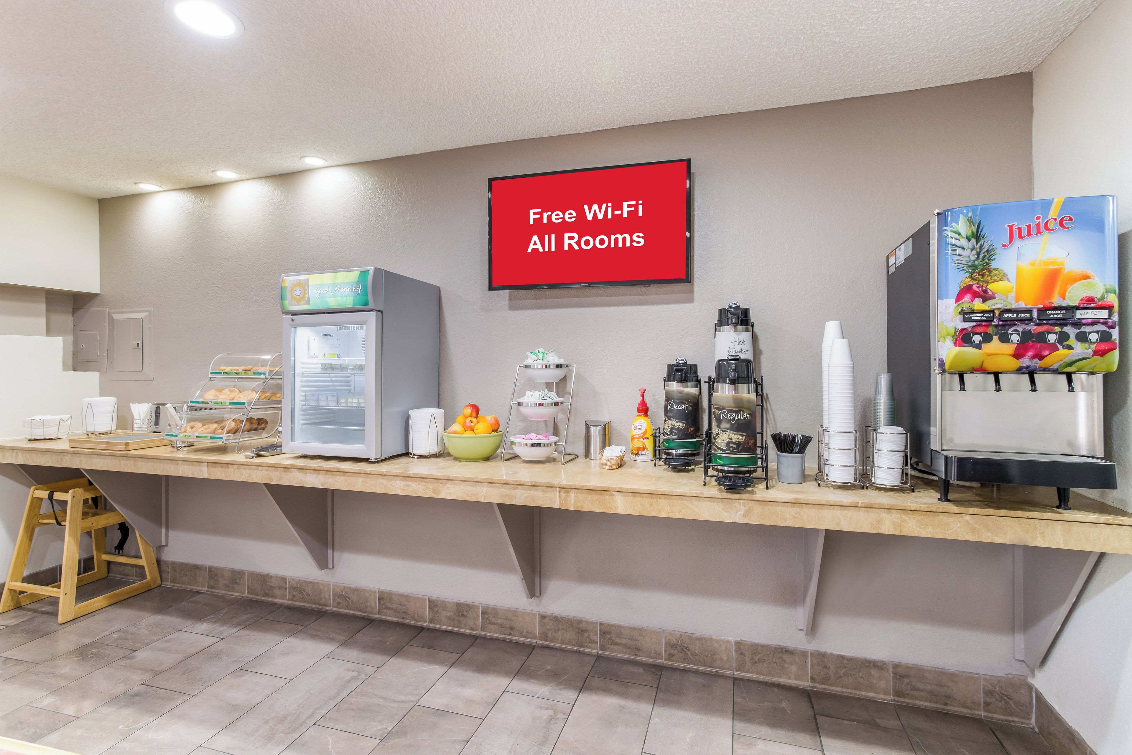 Een ontbijtruimte met zelfbediening, voorzien van een koelkast, koffieautomaten en een bordje met gratis wifi.
