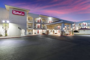 Ein Red Roof Inn mit mehrstöckiger Bauweise, einem überdachten Parkplatz und einem gut beleuchteten Eingang.