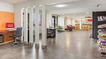 A hotel lobby with a reception desk, a seating area, and a breakfast buffet.