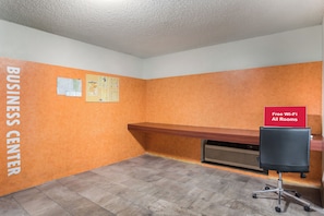 A business center with a bulletin board, a red sign indicating free Wi-Fi, and a desk with a chair.