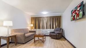 A living room with a sofa, armchair, coffee table, lamp, and a painting on the wall.