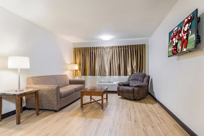 Ein Wohnzimmer mit Sofa, Sesseln, Couchtisch, Lampe und einem Bild an der Wand.