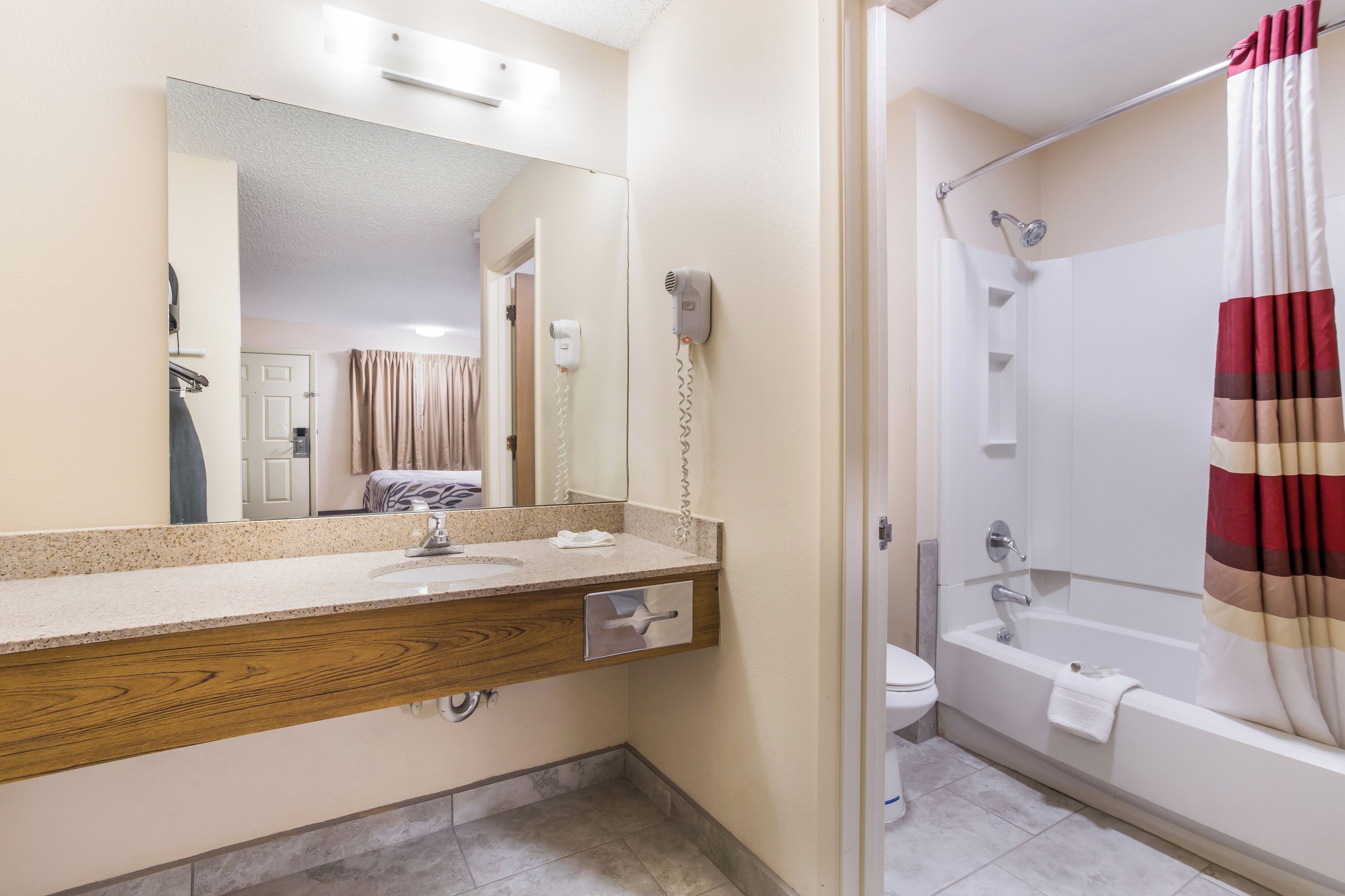 Une salle de bain équipée d’un lavabo, d’un miroir, d’un sèche-cheveux et d’un rideau de douche.