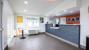 A reception area with a counter, chairs, a window, and a sign.