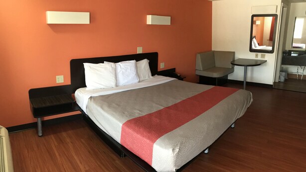 A hotel room with a bed, a desk, a chair, and a small table. - Motel 6 Troutville, VA (Troutville)