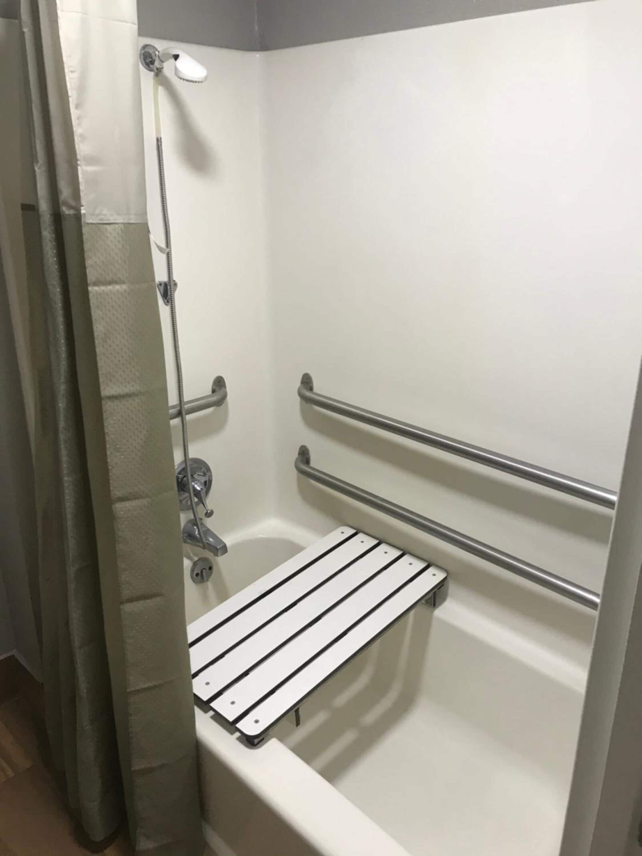 A shower with a handheld showerhead, a handheld shower attachment, and a grab bar.