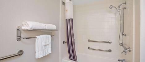 A modern bathroom with a bathtub, grab bars, a towel rack, and a shower curtain.