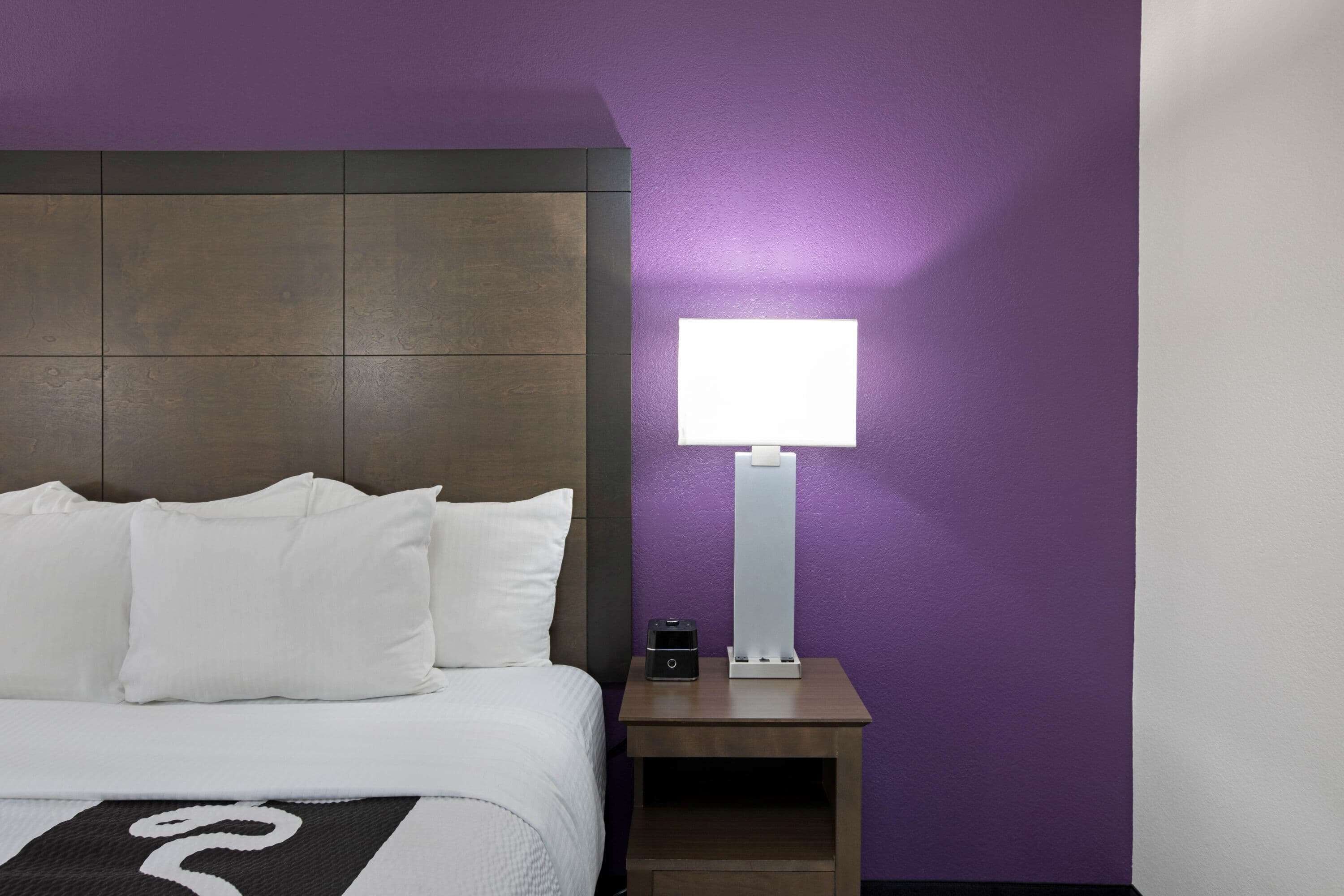 Une chambre d’hôtel avec un lit, une table de chevet et une lampe fixée au mur.