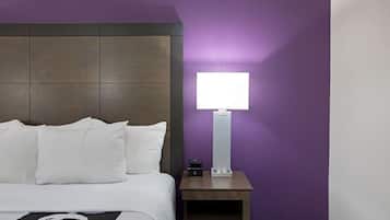 Une chambre d’hôtel avec un lit, une table de chevet et une lampe fixée au mur.