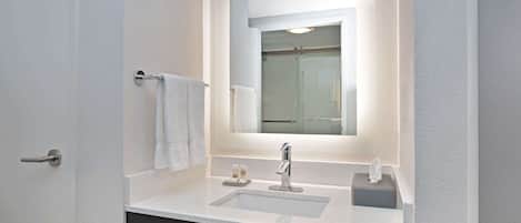 A bathroom with a white sink, a mirror, and a towel rack.
