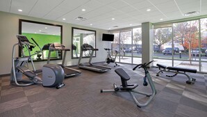Un gimnasio con cintas de correr, una elíptica y un banco para press de banca.