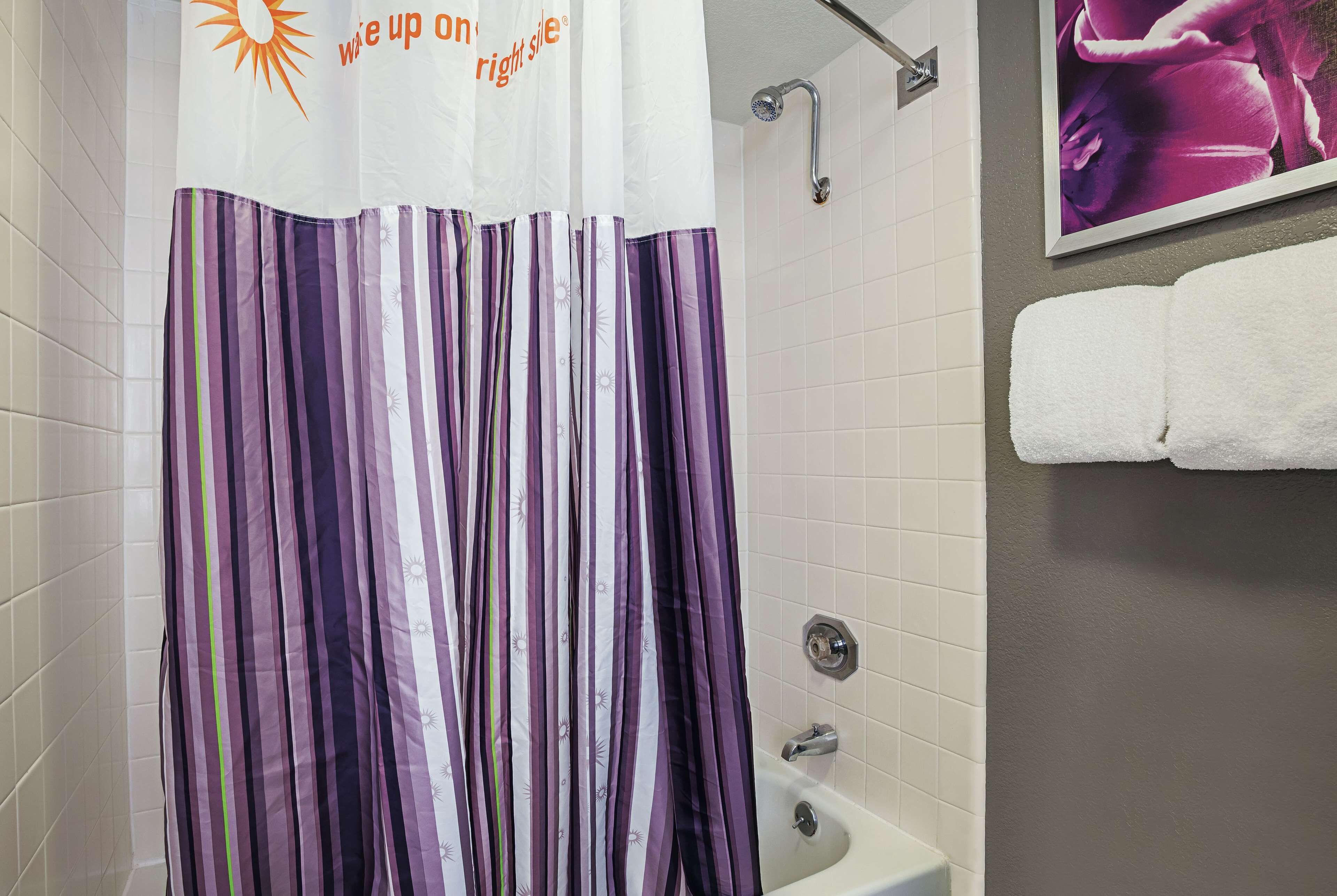 A bathroom with a striped shower curtain, a white bathtub, and a towel rack with a white towel.