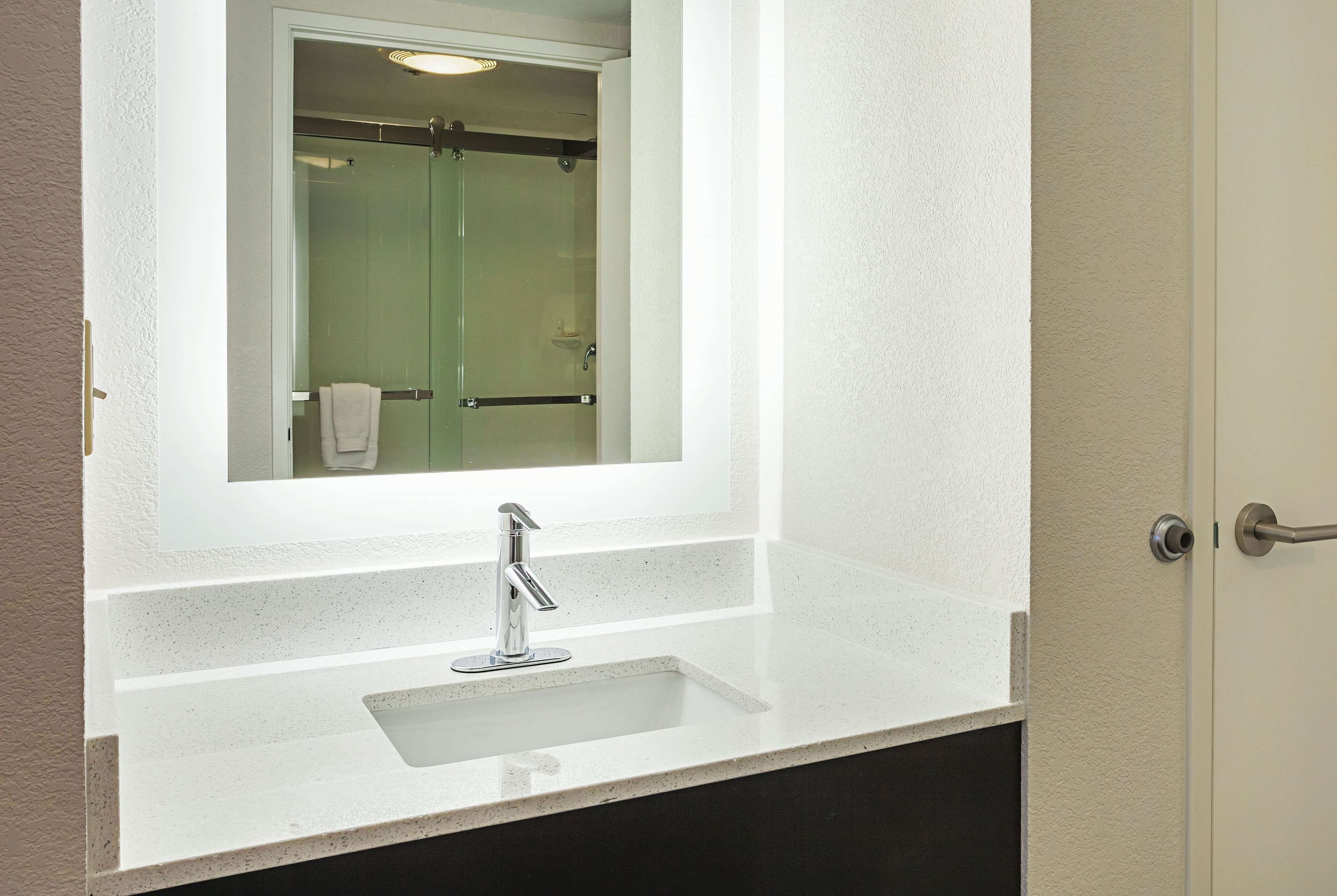 A bathroom with a white countertop, a sink, and a mirror above it.