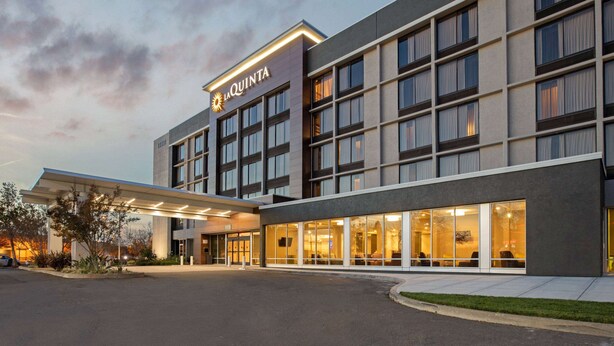 Un hotel con fachada moderna, ventanas amplias y acceso cubierto.
