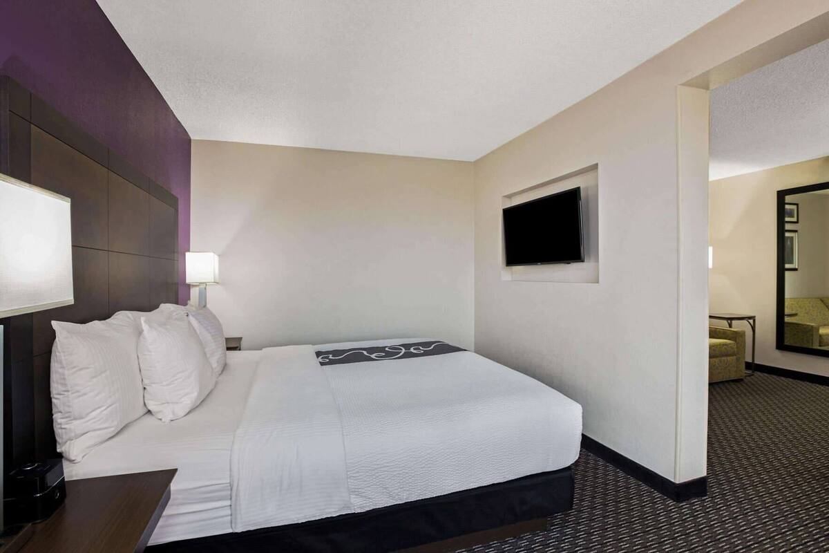 A hotel room with a bed, a TV, a desk, and a chair.