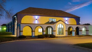 A modern building with a yellow facade, multiple arched windows, and a flat roof. - Days Inn by Wyndham Austin (Austin)