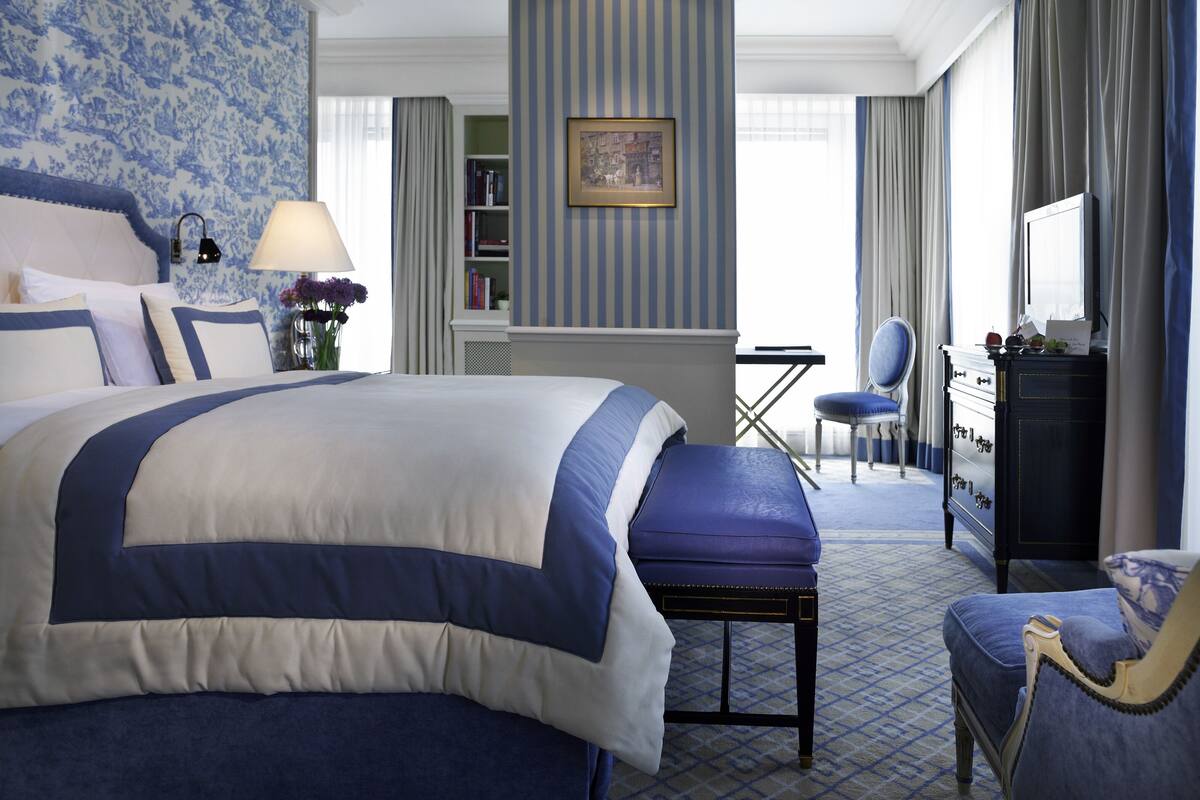 Ein Hotelzimmer mit einem großen Bett, einem Schreibtisch, einem Sessel und einem Schminktisch.