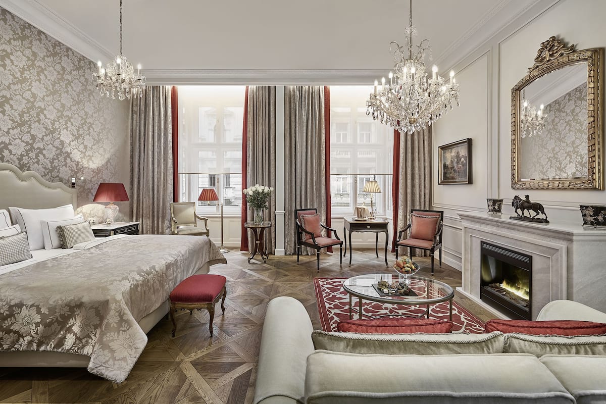 Ein luxuriöses Schlafzimmer mit einem großen Bett, einer Sitzecke mit Kamin und Blick auf die Stadt.