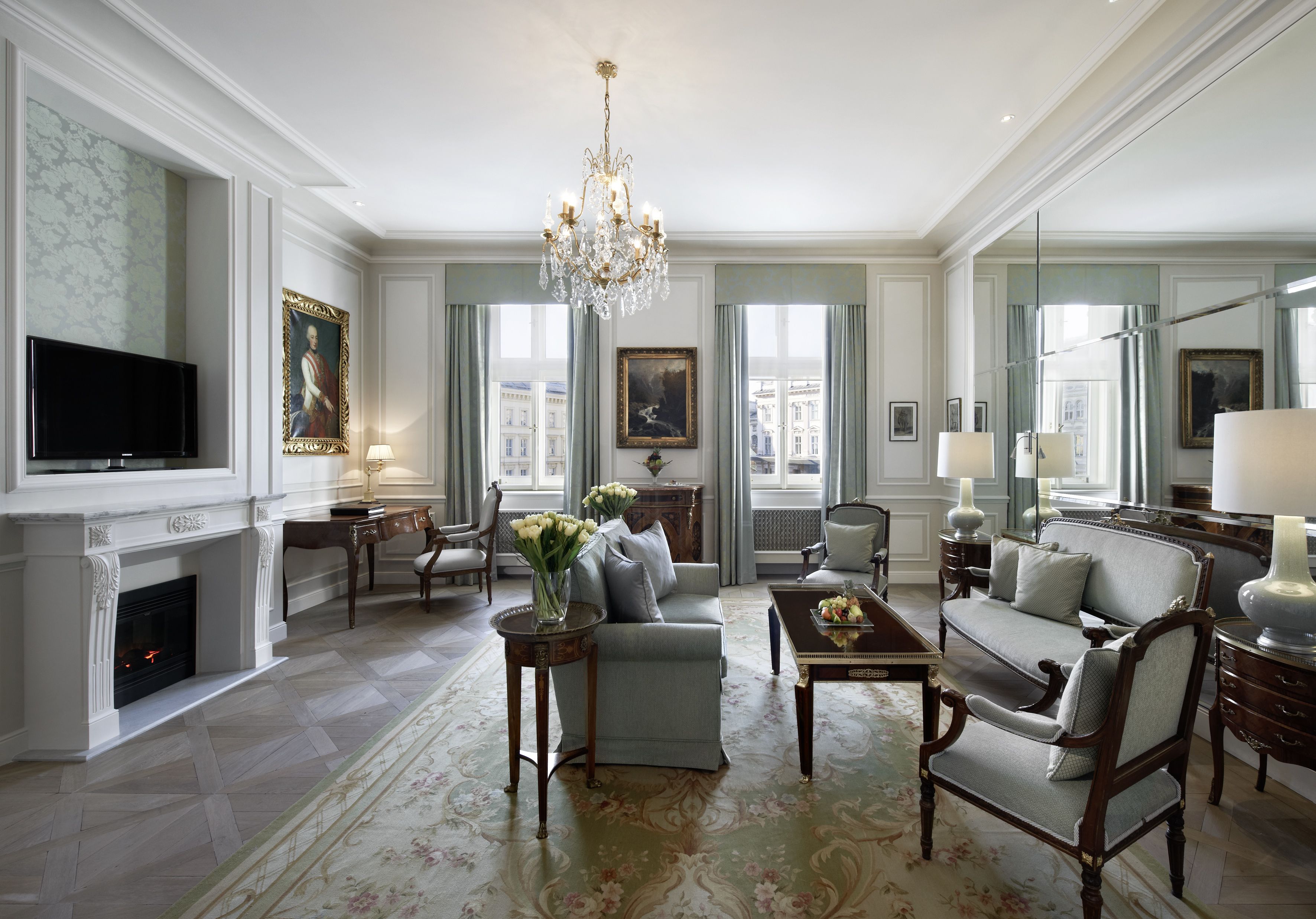 A spacious living room with a fireplace, elegant furniture, and large windows offering city views.
