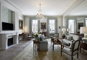 A spacious living room with a fireplace, elegant furniture, and large windows offering city views.