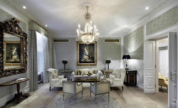 A luxurious living room with a chandelier, ornate furniture, and a large mirror.