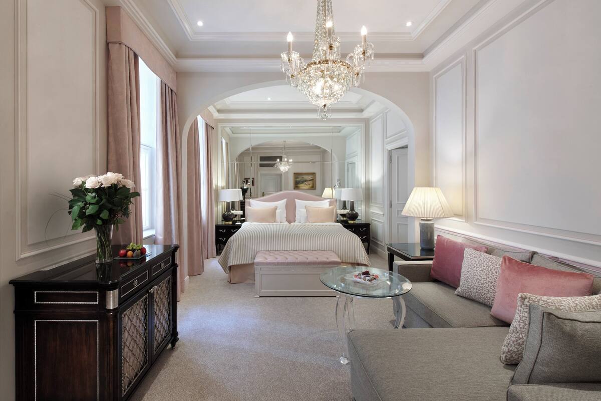 Ein luxuriöses Schlafzimmer mit einem großen Bett, einer Chandelierleuchtre und einem Glastisch.