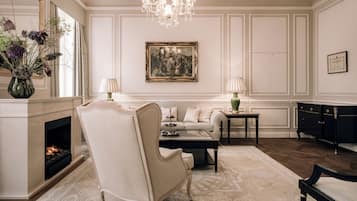 Un salon formel avec une cheminée, des meubles élégants et un lustre.