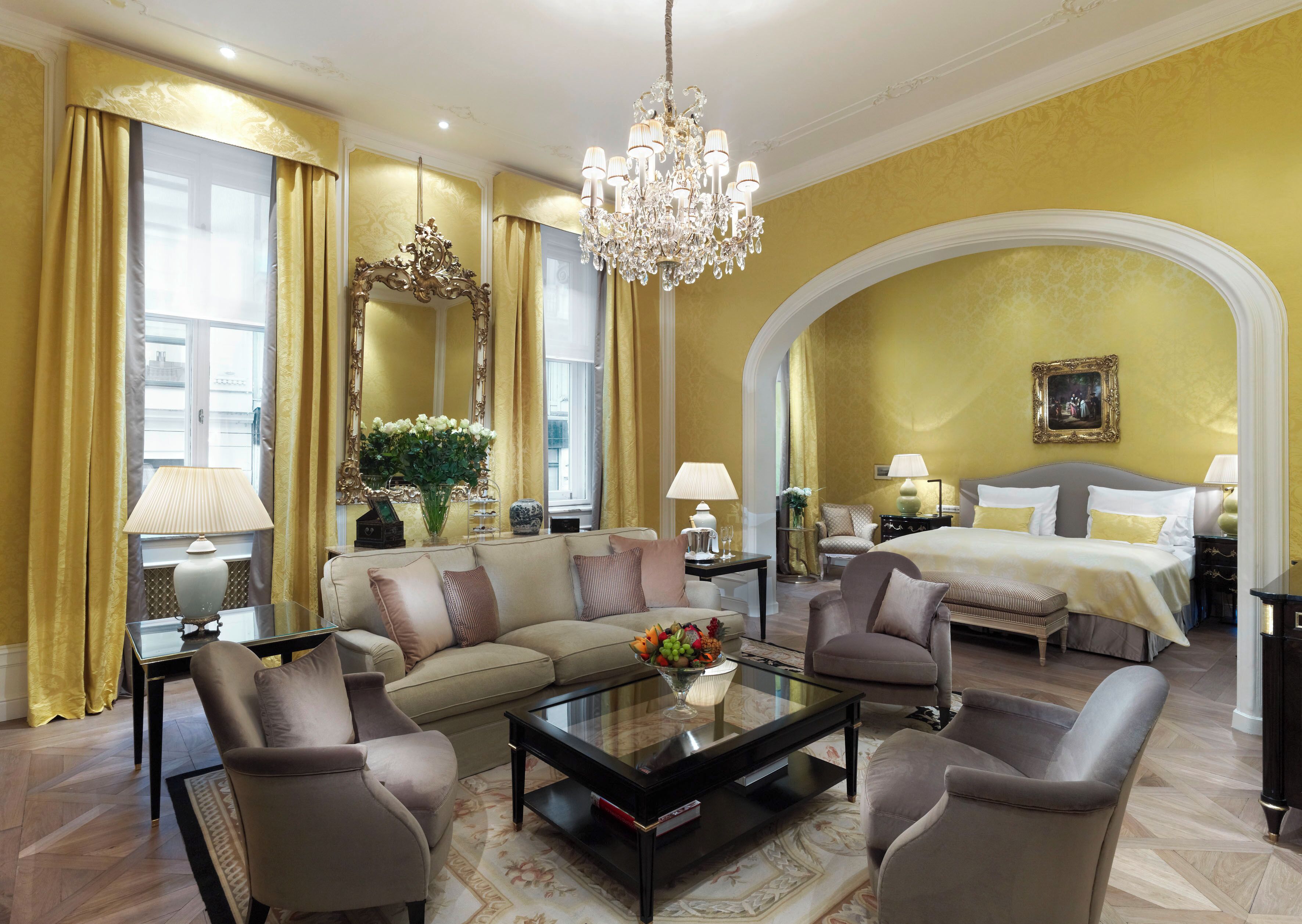 Een luxe hotelkamer met een groot bed, een bank, een salontafel en een kroonluchter.