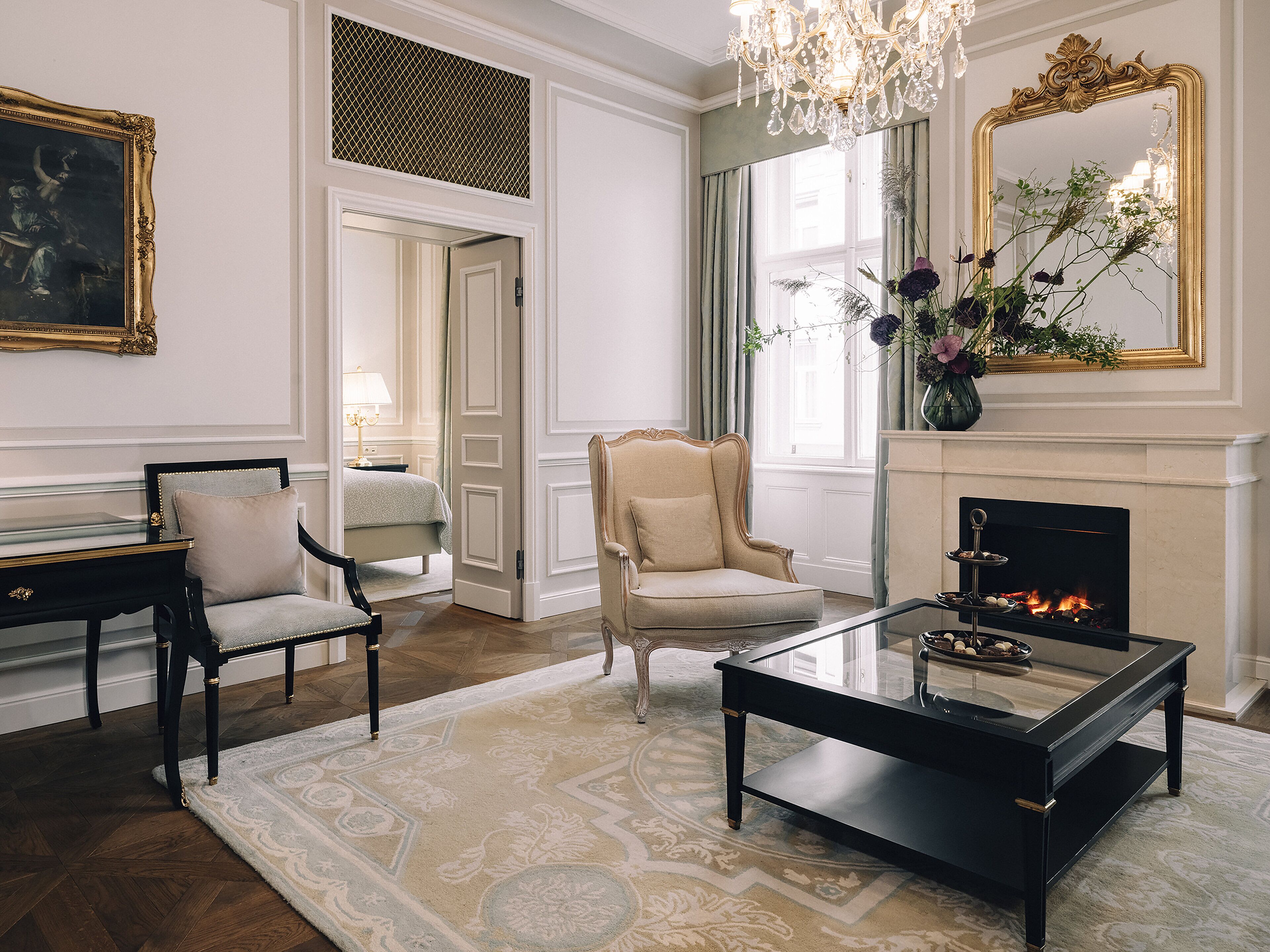 Ein elegantes Wohnzimmer mit Kamin, einem großen Spiegel und einer Kristallleuchter.