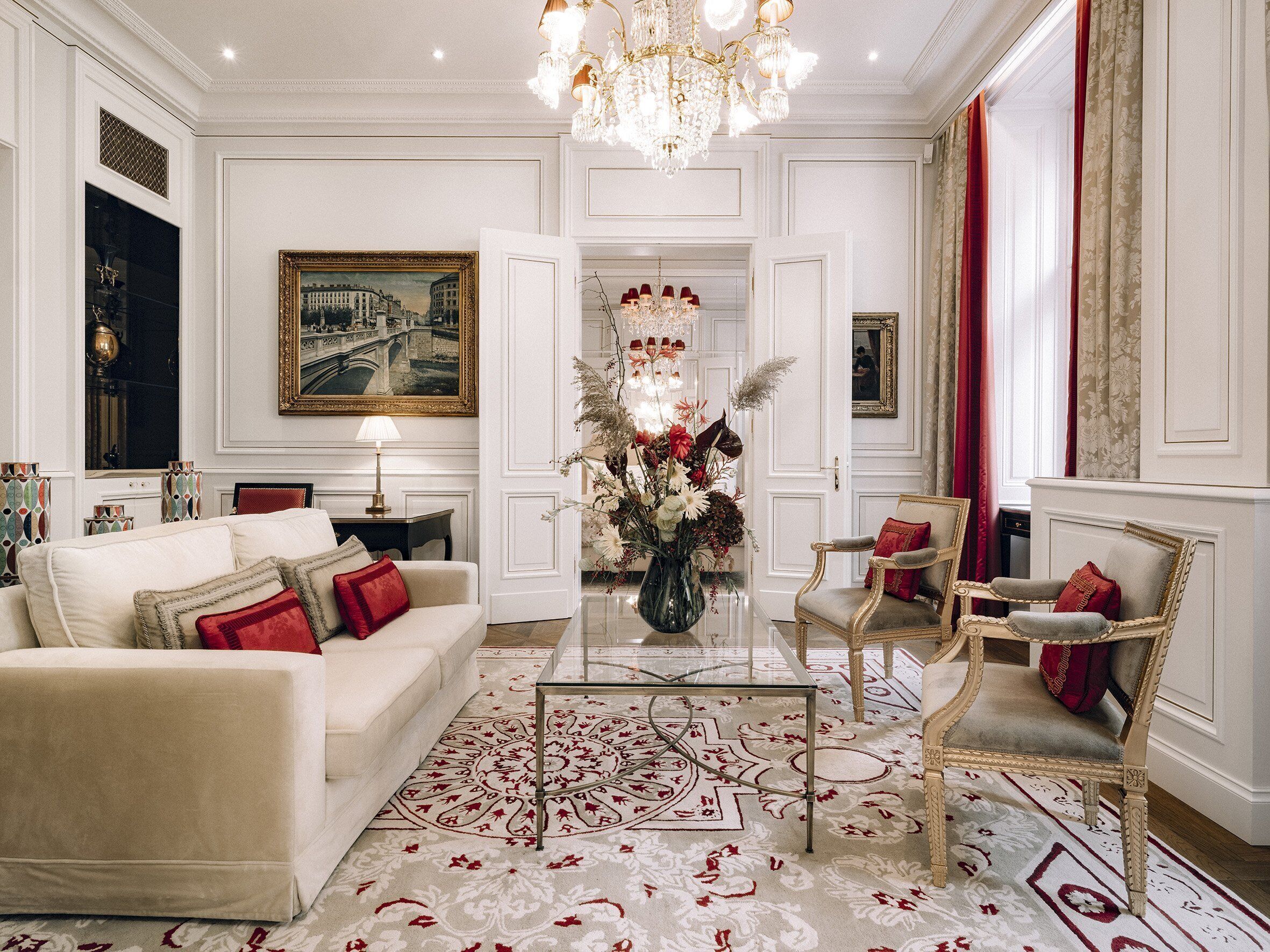 Un salon luxueux aux tons blancs, agrémenté de meubles élégants et d’un lustre.