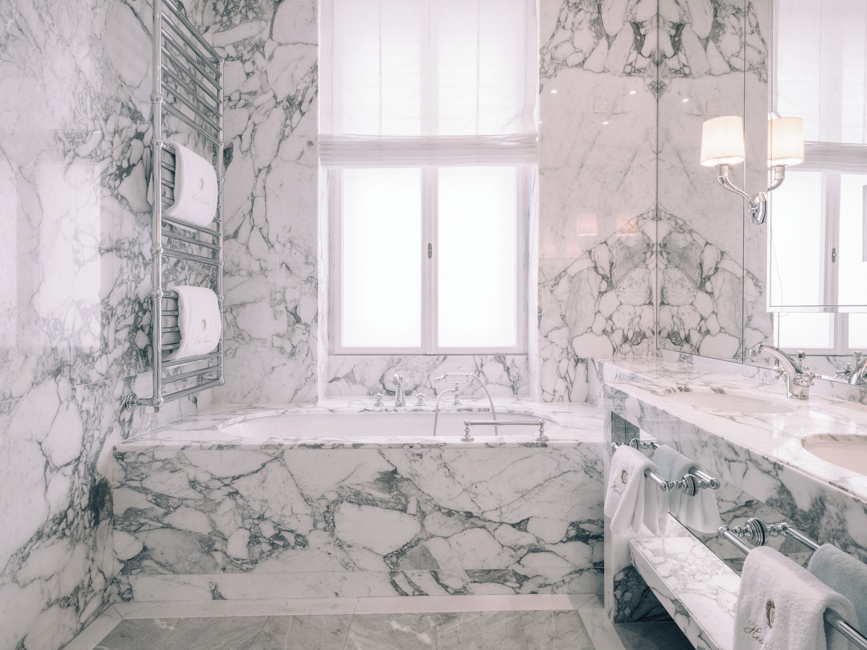 Un baño con lavamanos de mármol, bañera y un amplio ventanal.
