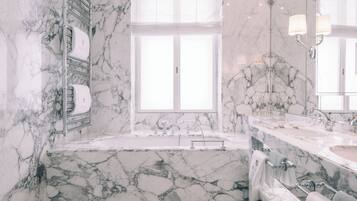 Un baño con lavamanos de mármol, bañera y un amplio ventanal.