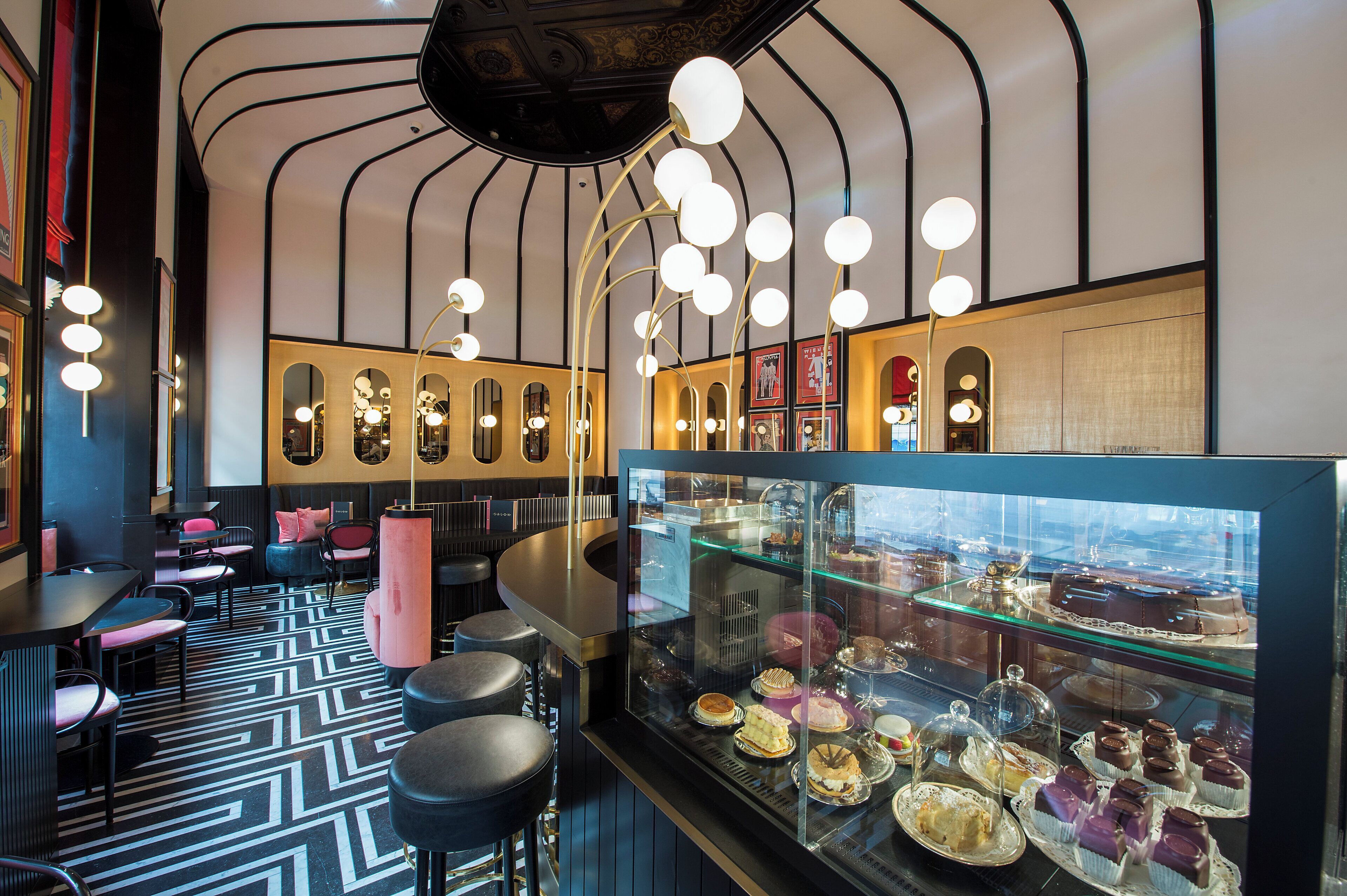 A modern interior with a bar area, seating, and a display case with desserts.