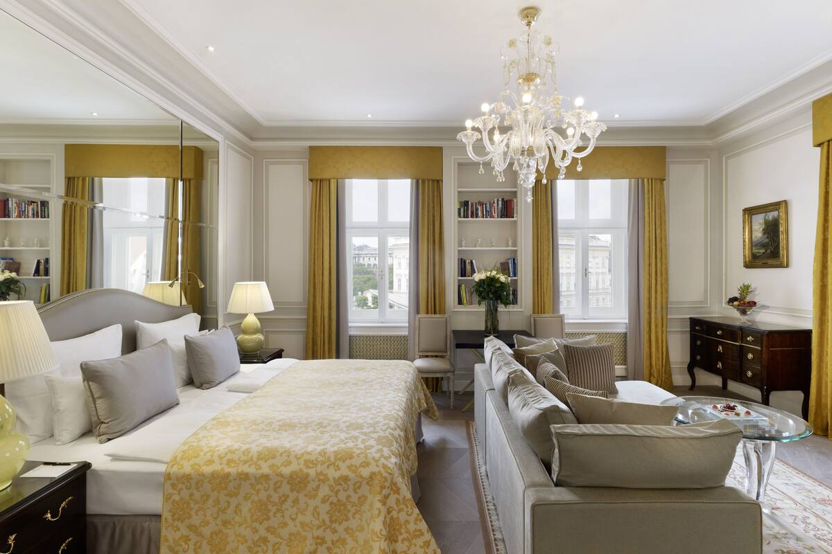 Ein geräumiges Hotelzimmer mit einem großen Bett, einer Couch, einem Schreibtisch und einem Chandelier.