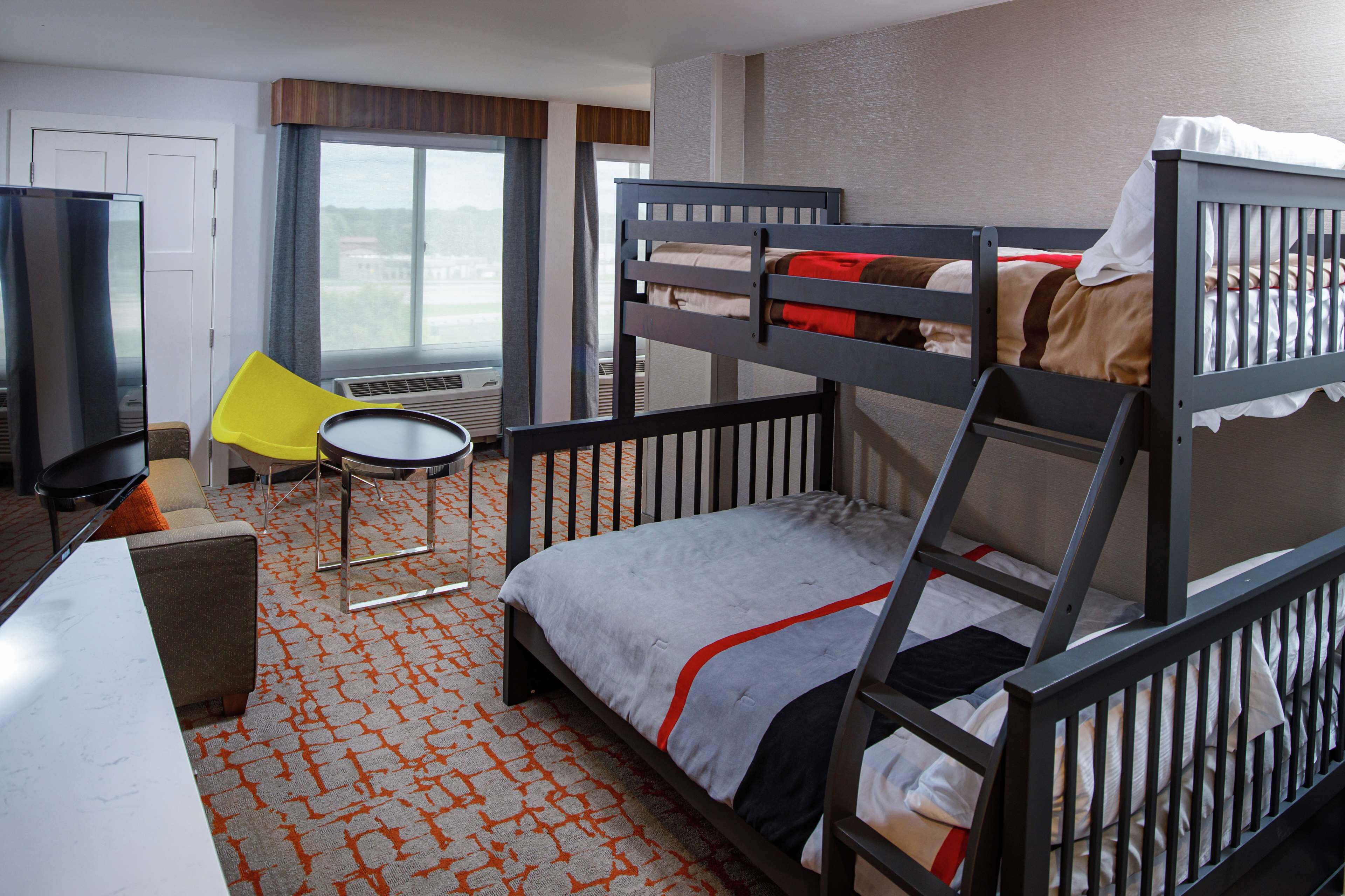 Une chambre d’hôtel avec un lit superposé, un bureau, une chaise et une petite table.