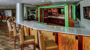 A bar area with a long counter, multiple seating options, and a variety of bottles and glasses. - DoubleTree by Hilton Appleton (Appleton)