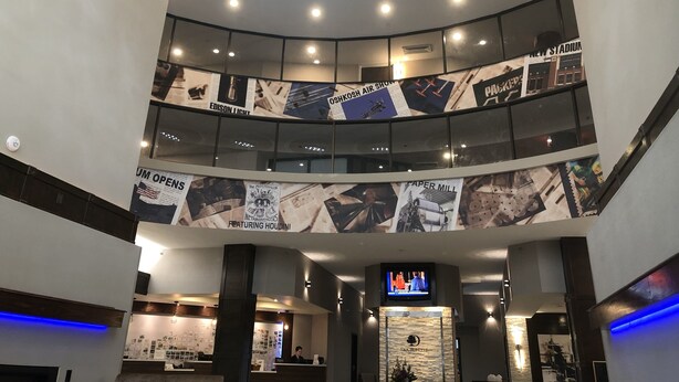 A modern hotel lobby with a curved ceiling, a central staircase, and a reception desk. - DoubleTree by Hilton Appleton (Appleton)