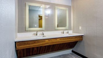 Un baño moderno con dos lavamanos, tocador de madera y espejos grandes.