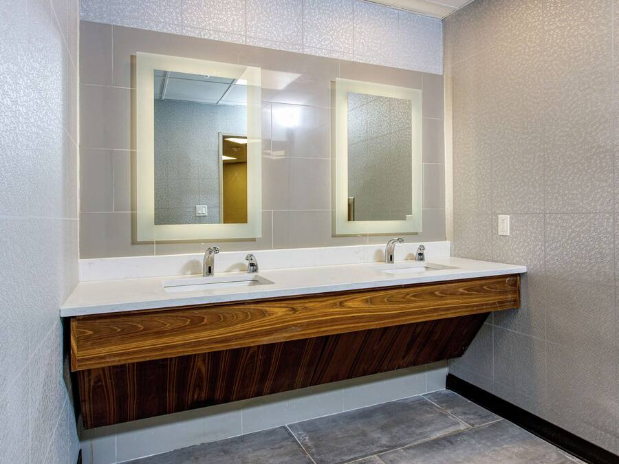Un baño moderno con dos lavamanos, tocador de madera y espejos grandes.