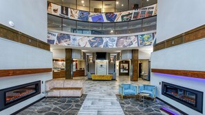 A spacious lobby with a central seating area, a fireplace, and a high ceiling with banners. - DoubleTree by Hilton Appleton (Appleton)