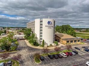 A hotel named DoubleTree by Hilton with a modern design, a parking lot, and surrounding greenery.