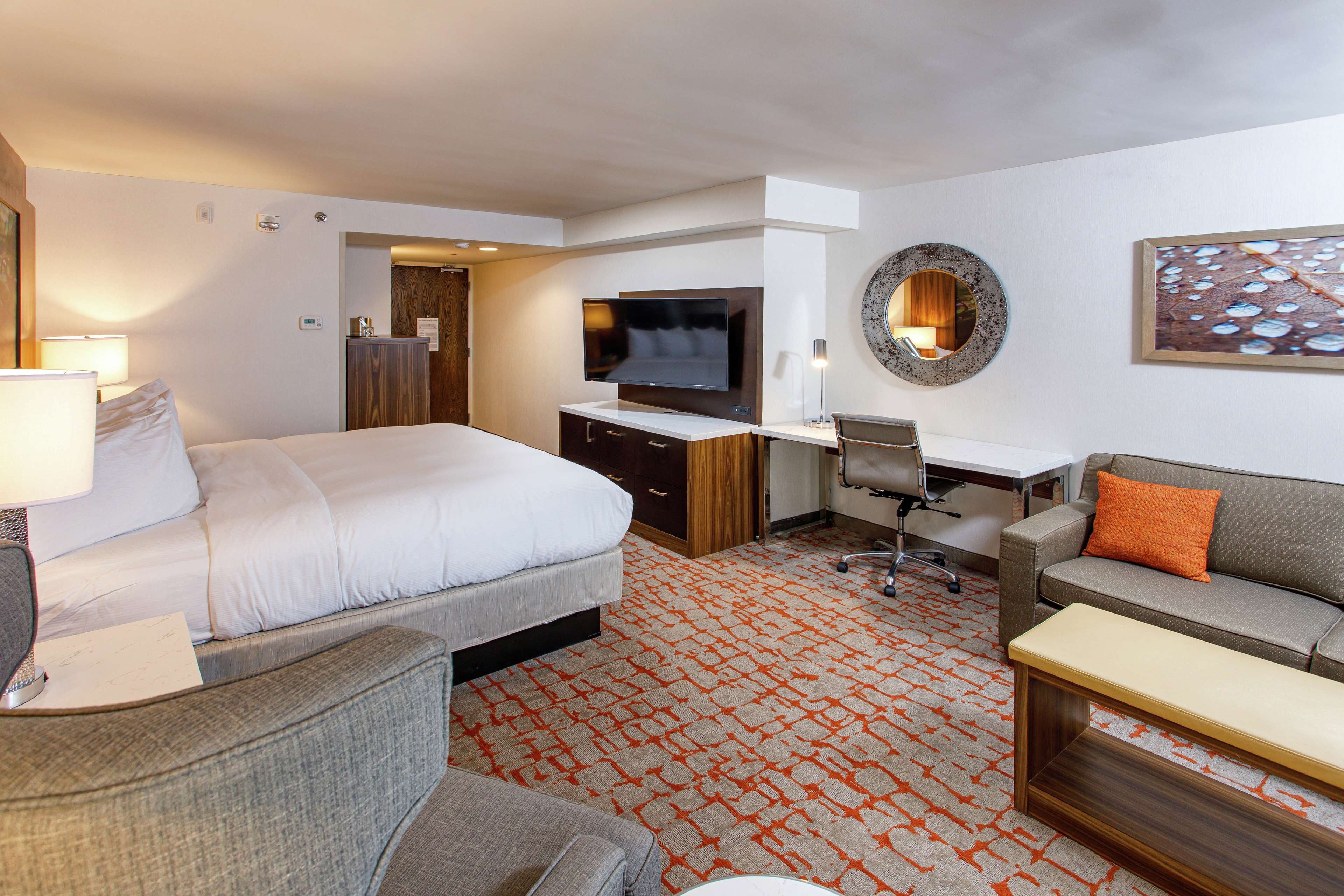 A hotel room with a bed, a desk, a sofa, and a TV.