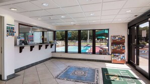 A reception area with a counter, a pool view, and a 'Quality' mat. - Quality Inn Little Creek (Virginia Beach)