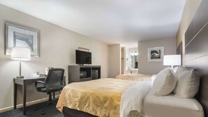 A hotel room with a bed, a desk with a computer, a chair, and a TV. - Quality Inn Little Creek (Virginia Beach)