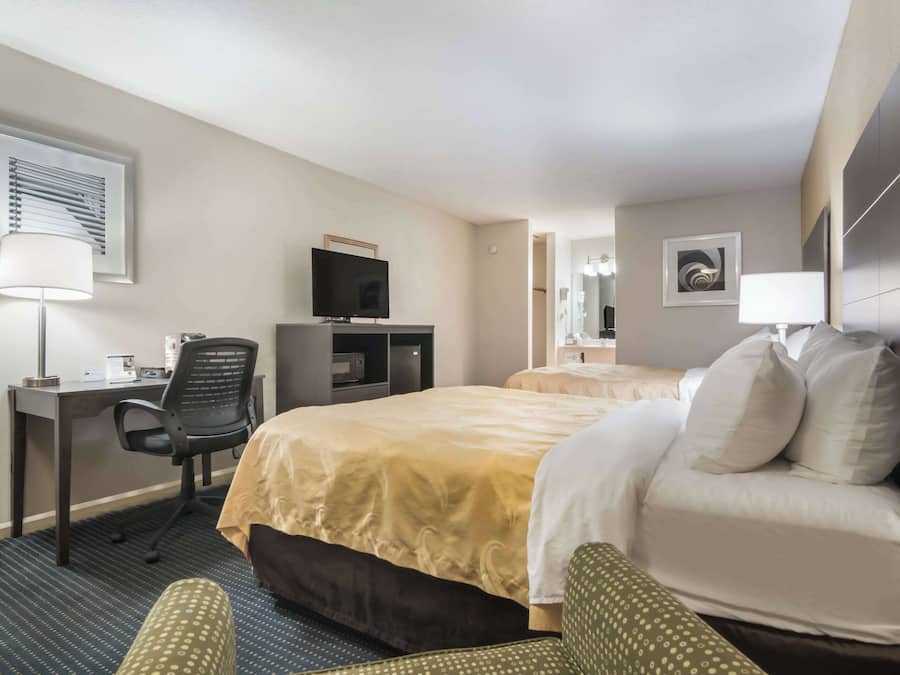 Une chambre d’hôtel avec un lit, un bureau avec un ordinateur, une chaise et un téléviseur.