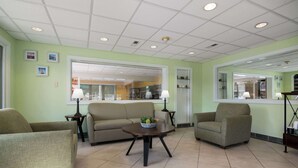 A room with a sofa, armchairs, a small table with a plant, and a mirror on the wall. - Quality Inn Little Creek (Virginia Beach)