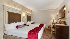 A hotel room with two beds, a desk, a chair, and a dresser.
