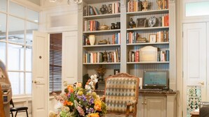 A traditional library with bookshelves, a chandelier, and classic furniture.