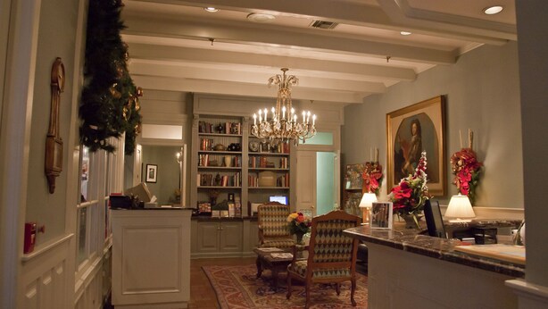 A cozy living room with a fireplace, a bookshelf, and a dining area with chairs.