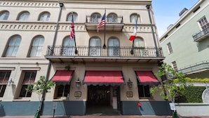 A historic building with a red awning, multiple flags, and a brick entrance.